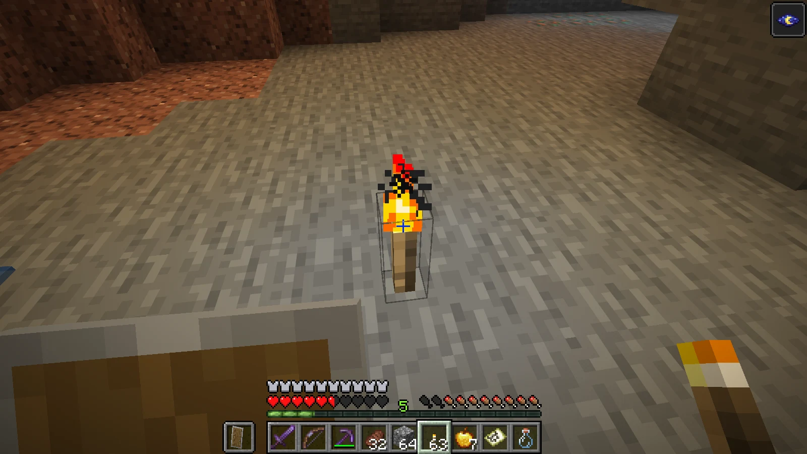 A torch lighting the floor of the cave during the underground journey